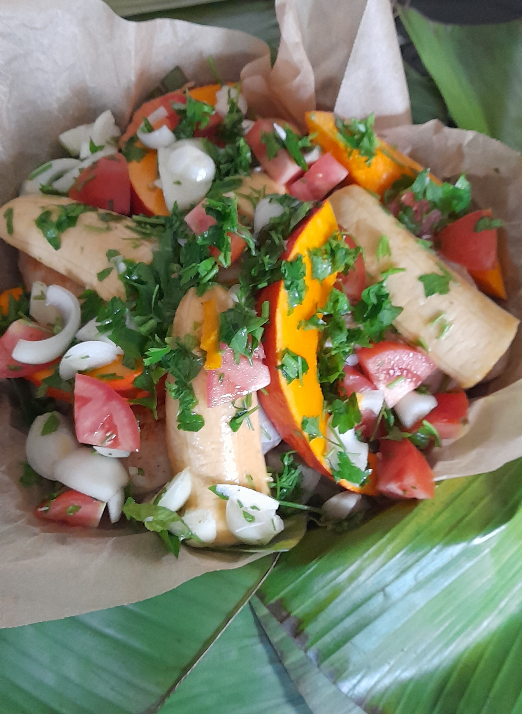 Bougna plat emblématique de Calédonie Il est composé de différents tubercules tels que l'igname, la patate douce et le taro, avec du poulet, du poisson ou des crevettes cuites au four avec des feuilles de bananier et du lait de coco.